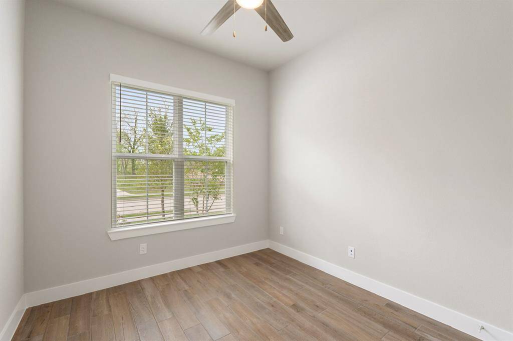 This secondary bedroom is filled with natural light and offers a peaceful view of the greenbelt across the street—perfect as a guest room, nursery, or home office.