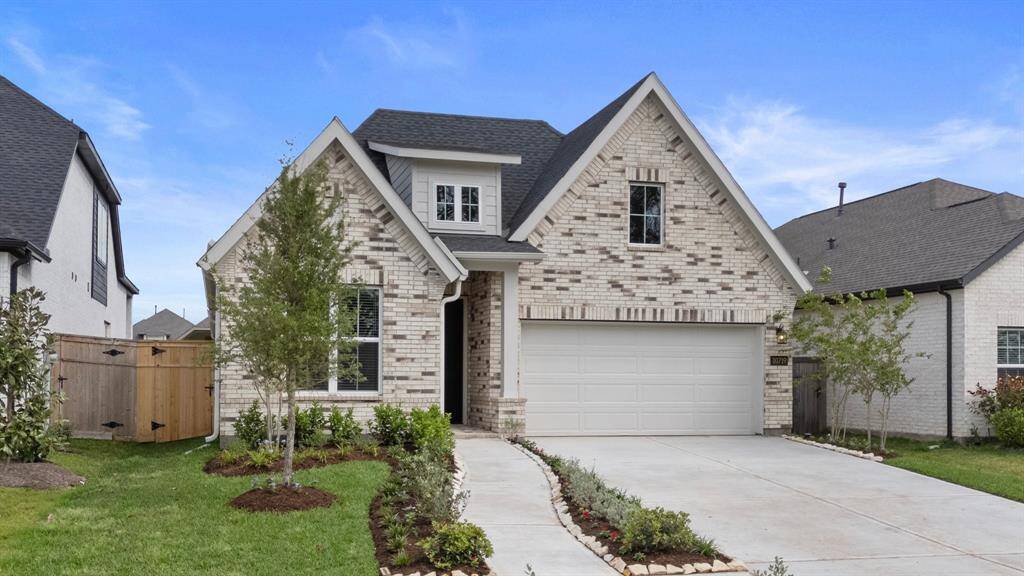 This beautifully landscaped front yard leads to a striking brick elevation with fresh exterior finishes, a two-car garage, and a welcoming covered entry.
