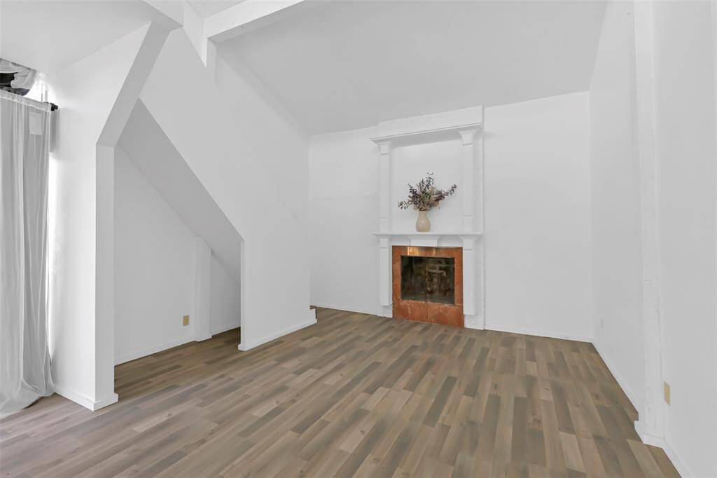 Bright living space with a high ceiling and modern LVP flooring. Features a decorative fireplace and a unique architectural alcove, offering potential for creative decorating.