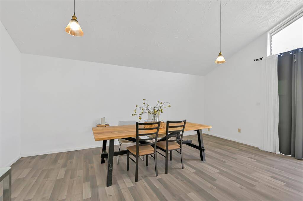 Bright breakfast area with high ceilings, modern pendant lights, and a large window create a spacious and inviting atmosphere.