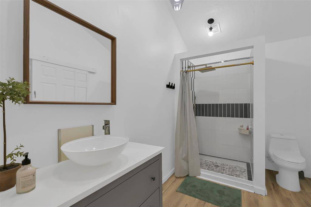 This bathroom features a modern design with a sleek vessel sink, vanity and a spacious shower with a stylish tile accent.