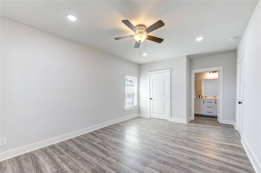 This bright, spacious room features modern wood flooring, neutral walls, a ceiling fan, and recessed lighting. It includes a window for natural light and an en-suite bathroom for added convenience.