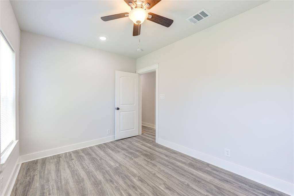 Bright and inviting bedroom featuring elegant flooring, ample natural light, and a modern ceiling fan.