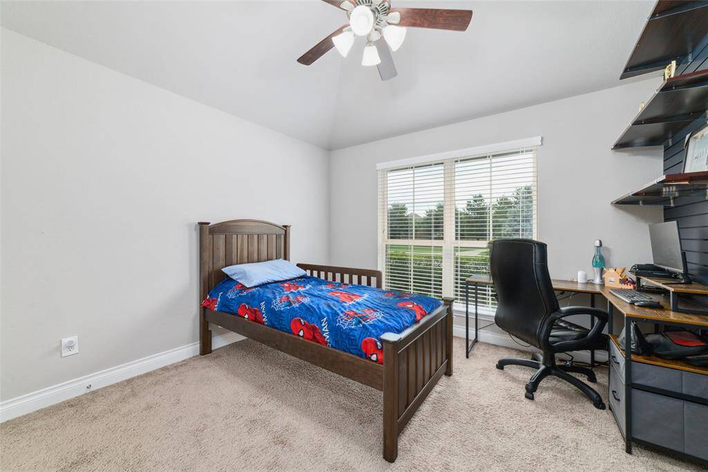 Bright and spacious secondary bedroom featuring a ceiling fan, large window, and a custom slat wall with built-in shelving, and walk in closet