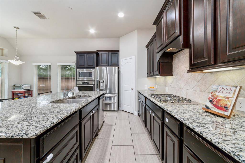 Expansive kitchen island with sleek granite countertops, a neutral backsplash, and a gas stove—perfect for cooking and entertaining.