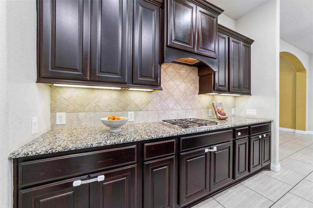 Kitchen features rich dark cabinetry, a gas stove, ample counter space, and under-cabinet lighting for added functionality and ambiance