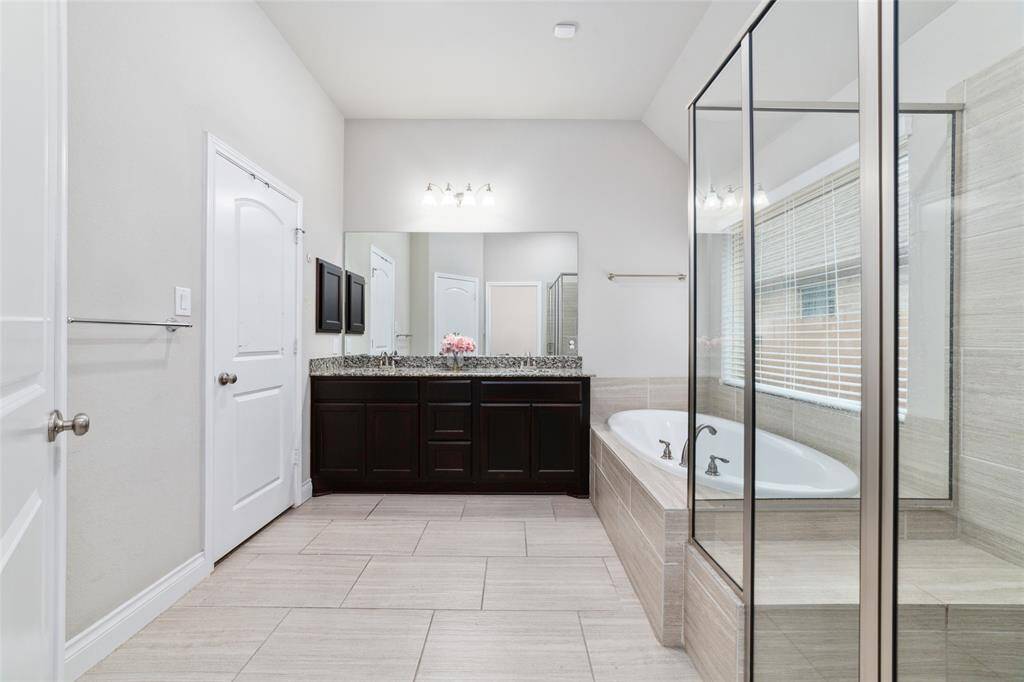 Primary bath boasts an elongated soaking tub, separate shower with built-in bench, and a large walk-in closet with seasonal rods and built-in shelving (closet not shown)
