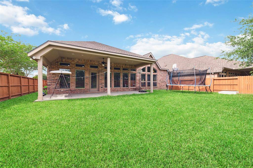 Wide-angle view of the expansive backyard, complete with a covered patio, perfect for outdoor relaxation and entertaining