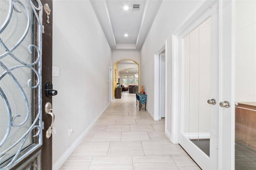 Inviting wide entryway with neutral tile flooring, elegant tray ceilings, and recessed lighting, creating a bright and welcoming atmosphere