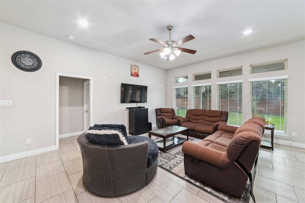 Inviting living room with neutral tile flooring, abundant natural light, and a ceiling fan for added comfort and style