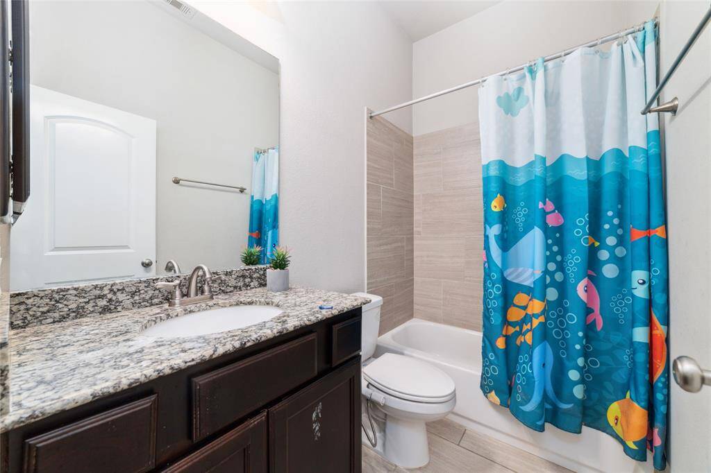 Well-appointed full bathroom featuring a tub/shower combo and a stylish granite countertop, offering both functionality and elegance
