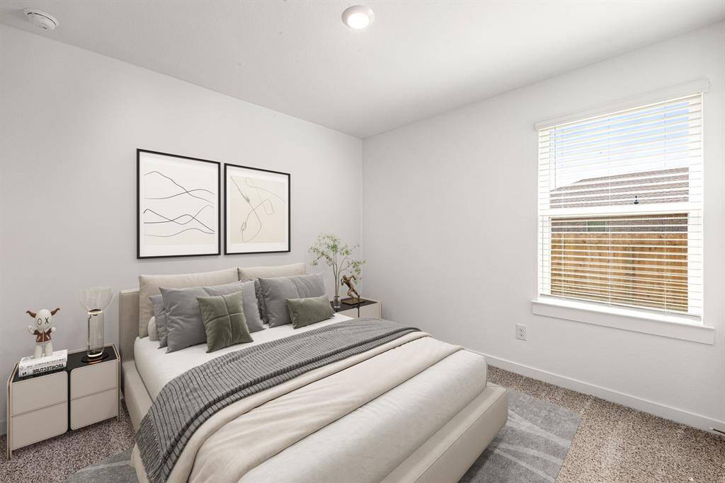 This bright and inviting bedroom features a large window that fills the space with natural light, highlighting the soft, neutral color palette and plush carpeting. The clean white walls and modern trim offer a fresh canvas, perfect for personalizing your sanctuary. Ideal for rest and relaxation, this room provides a peaceful retreat with a serene view of the quiet neighborhood outside.