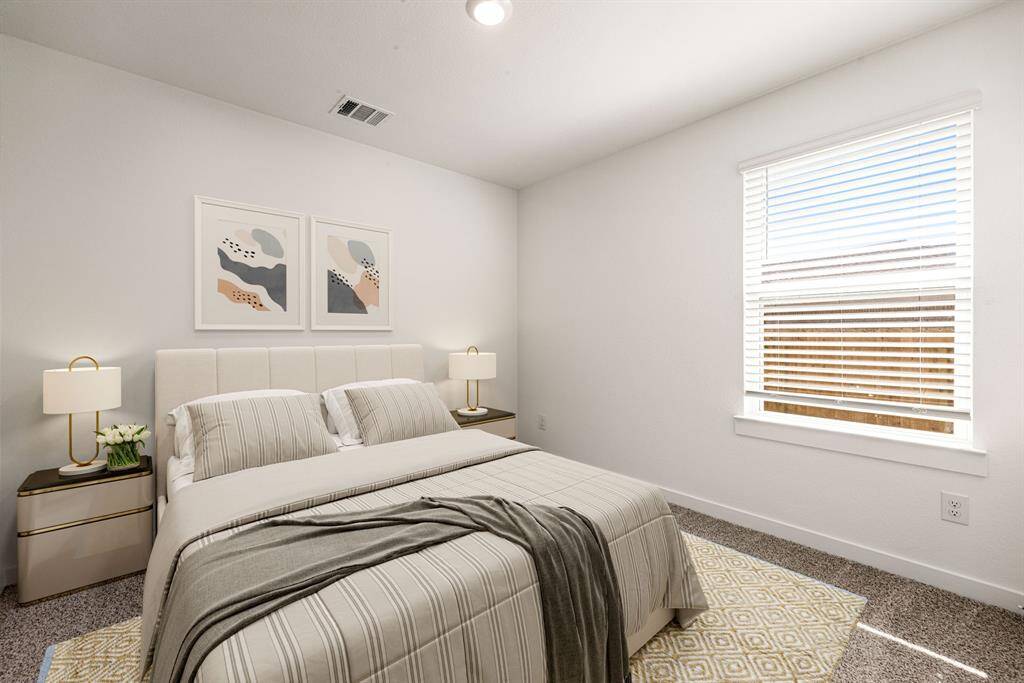 This bright and inviting bedroom features neutral tones and plush carpeting, complemented by a large window that fills the space with natural light. The clean lines and simple design create a serene atmosphere, perfect for rest and relaxation.