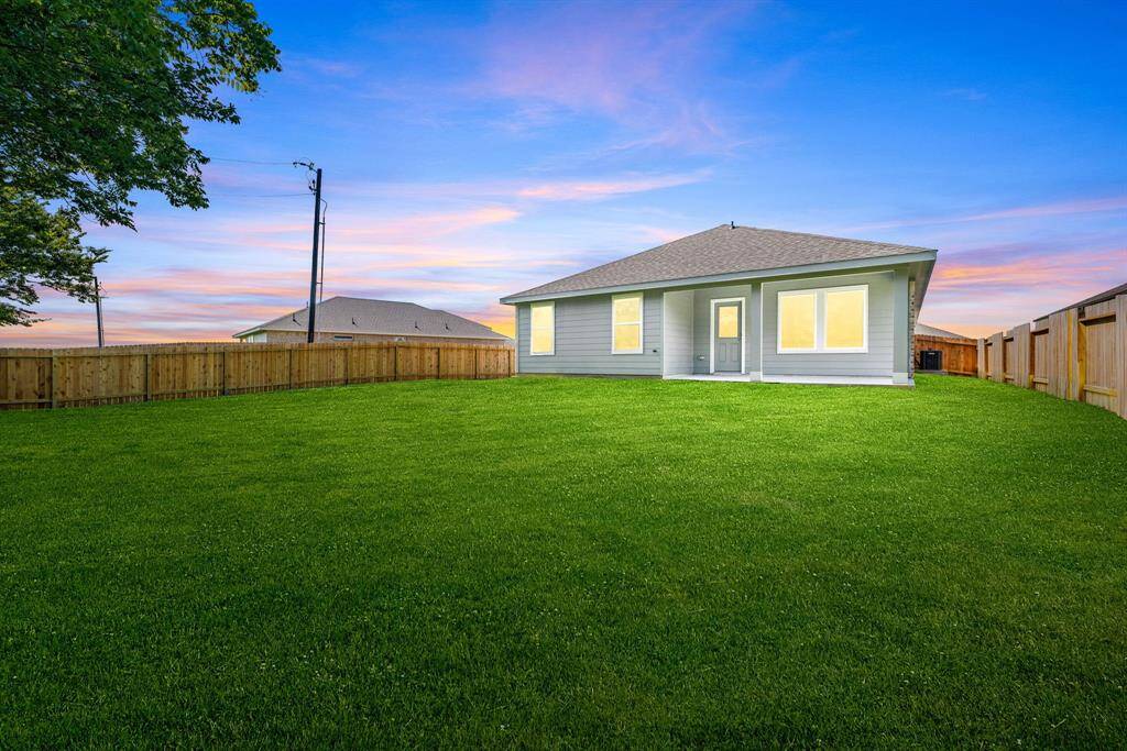 Step into this inviting backyard oasis featuring a spacious lawn, a charming covered patio, and a paved walkway that adds both function and style.