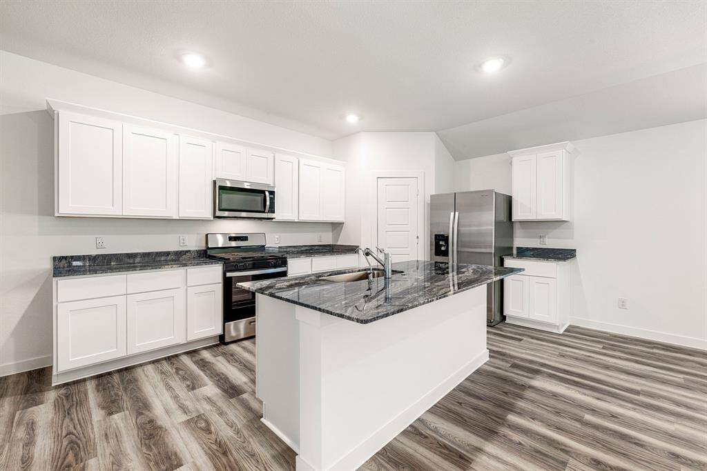 Step into this stunning modern kitchen featuring crisp white shaker cabinets, sleek stainless steel appliances, and luxurious granite countertops. The spacious island with undermount sink and bar seating is perfect for entertaining, while rich wood-look flooring adds warmth and elegance. A perfect blend of style and functionality, this space is ready for your culinary creativity.