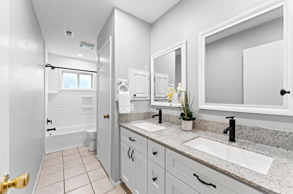 The hall bath features a tile surround tub and shower combination.
