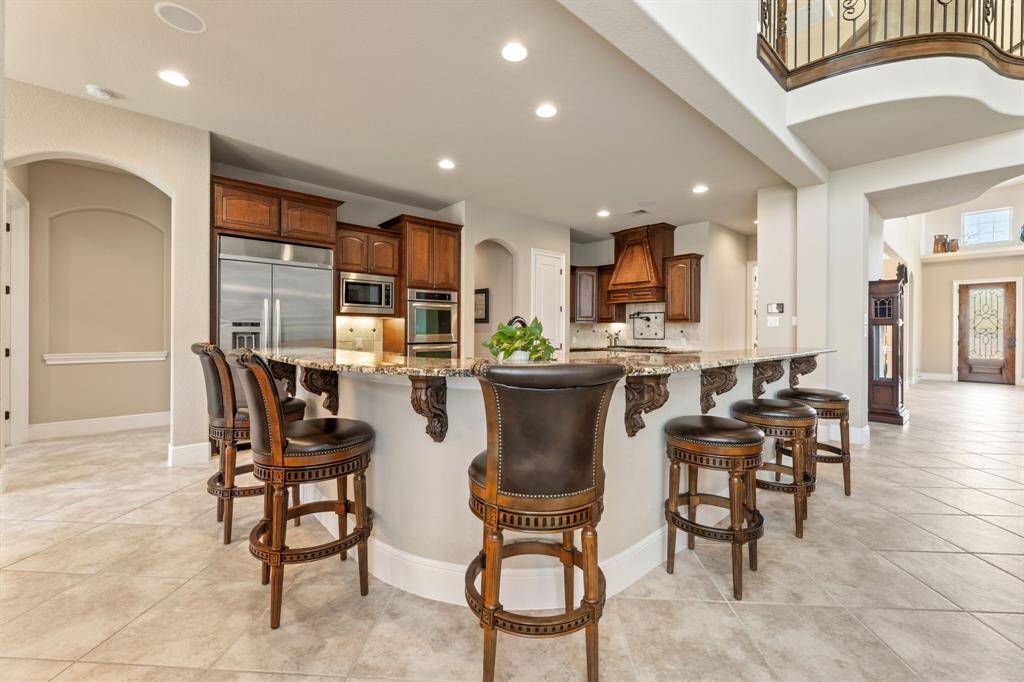 The kitchen seamlessly connects to the living area, with a raised curved bar providing additional seating. Ornate details add a touch of refinement to the space.