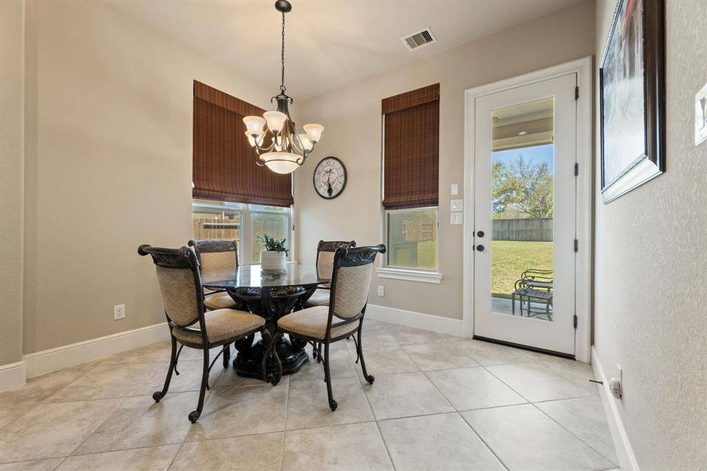 A bright and inviting space, this breakfast area is positioned in a sunlit corner with large windows and a glass-paneled door framing the backyard view.