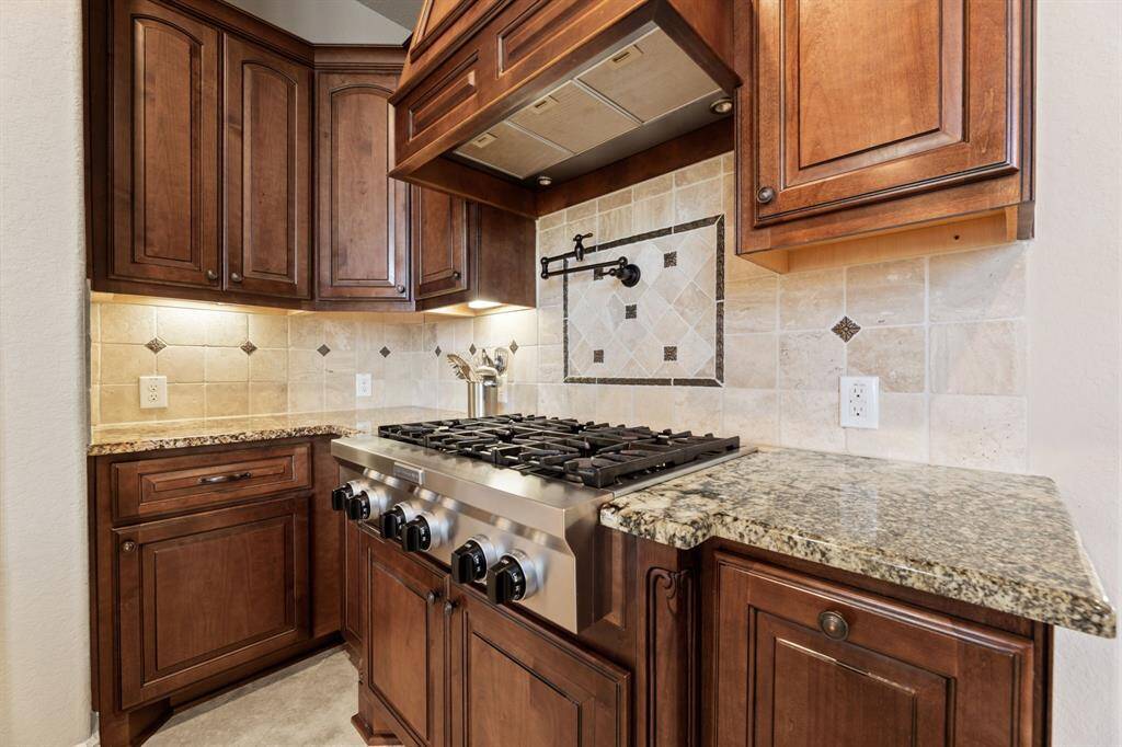 The warmth of the maple and alder wood cabinetry is beautifully highlighted by a subtly textured backsplash, adding depth to the design.