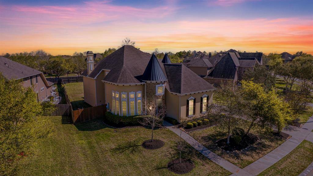This home’s striking facade glows under twilight, resembling a stately castle with elegant curved walls and turret-like features. The expansive lot adds to its grandeur.
