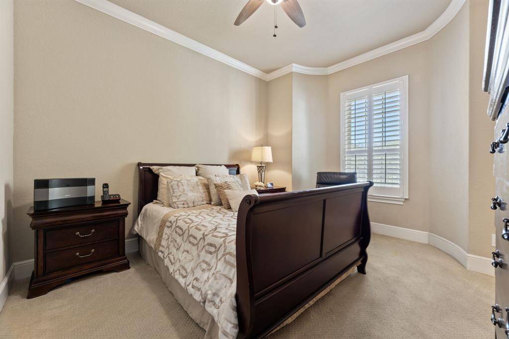 This bedroom is a serene retreat featuring soft neutral tones, crown molding, and a curved wall detail that adds architectural interest.
