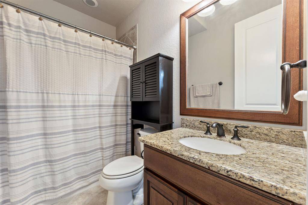 A refined bath with a wood-framed mirror and matching vanity, complemented by a separate shelf for added convenience.