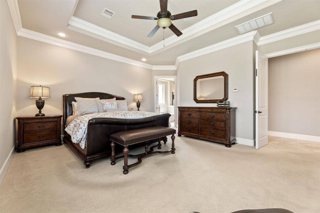 Dark wood furnishings add a rich contrast to the room’s soft palette, while the en suite bath enhances its luxurious feel.