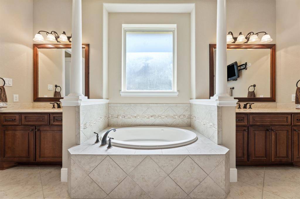 The stunning focal point of the bath—a luxurious tub framed by twin columns and elegant tilework—creates a spa-like atmosphere.