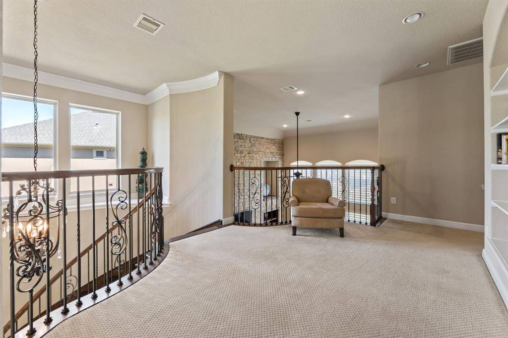 The wide, open upstairs landing is framed by classic black railings, brightened by oversized picture windows and offering a view below.