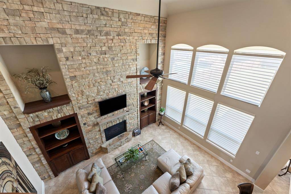 Looking down from the upstairs level, the full stone wall with its grand fireplace and twin rows of windows creates a striking visual impact.