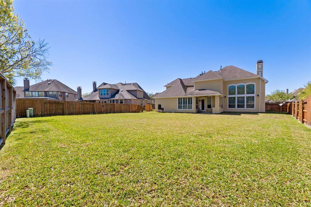 The home’s rear is framed by a lush, fenced backyard with neatly trimmed grass.