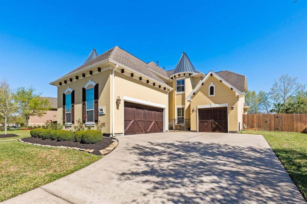 A spacious driveway leads to the attached three-car garage, featuring charming wooden doors.