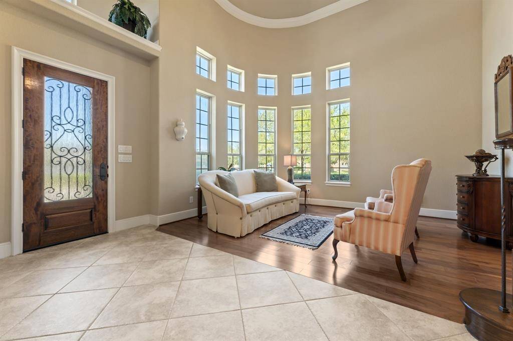 Step into a magnificent foyer where high ceilings and a curved wall lined with tall windows create a stunning first impression. The perfect space to welcome guests in style.