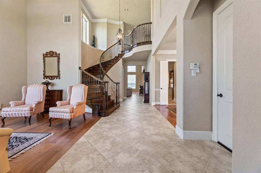 A breathtaking scene unfolds upon entry, with a sweeping staircase drawing the eye upward. The rich contrast of dark wood against light neutrals enhances the home’s elegance.