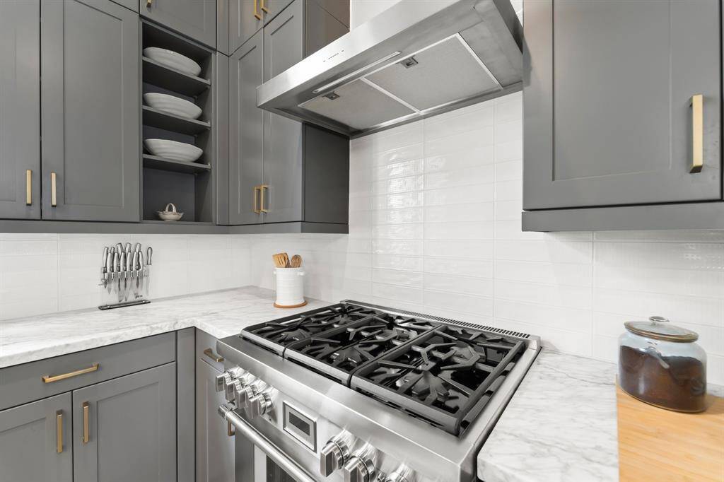 The kitchen features top-of-the-line Thermador stainless steel appliances, including a 6-burner professional-grade gas range with a vent hood.