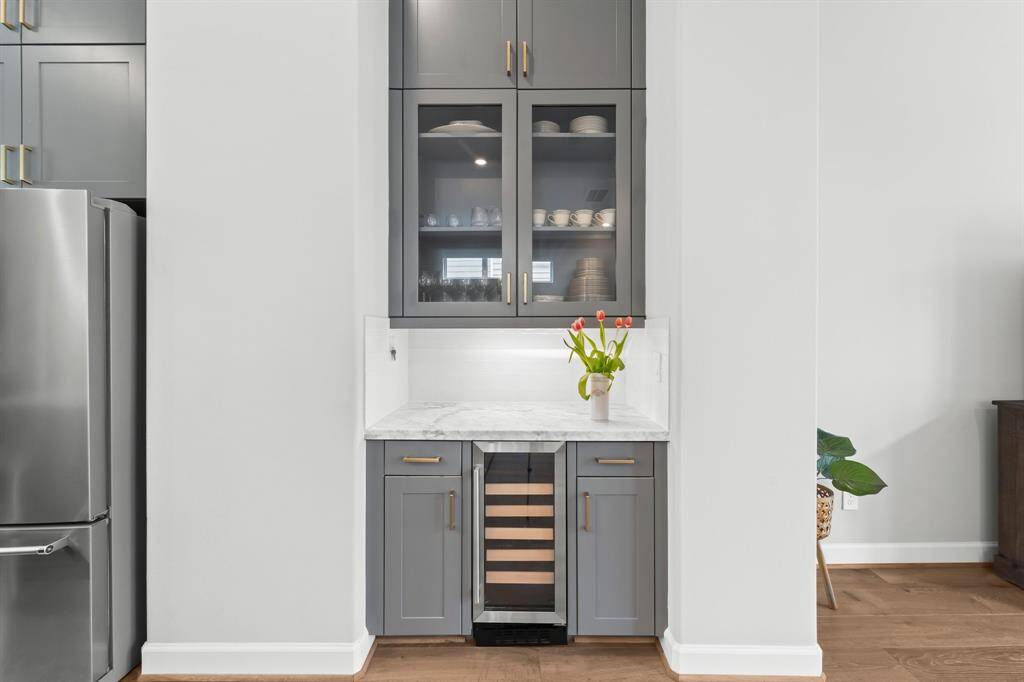 Enhance your kitchen experience with a stylish dry bar featuring glass-front cabinets and a built-in wine fridge.