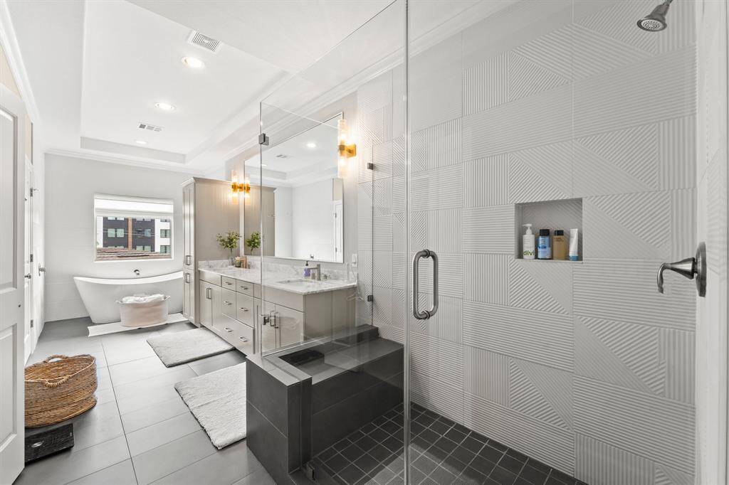 Spacious ensuite bath featuring a large walk-in shower, luxurious soaking tub, and sleek modern tiles.