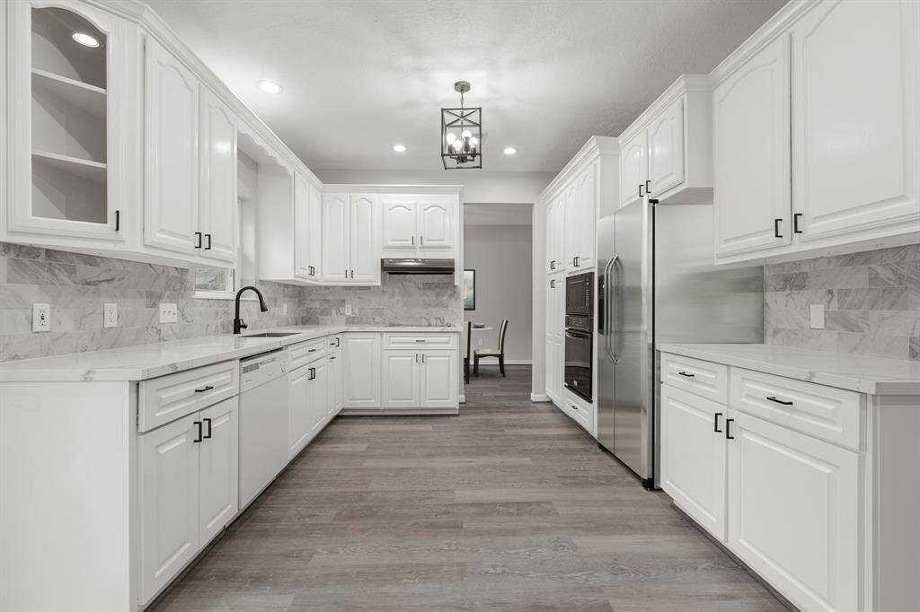 Look how perfect this kitchen is for entertaining! There is plenty of counter space and room for storage in this amazing kitchen! Beautiful white cabinets, quartz countertops, stylish and freshly installed backsplash, recessed lighting, and vinyl plank floors.
