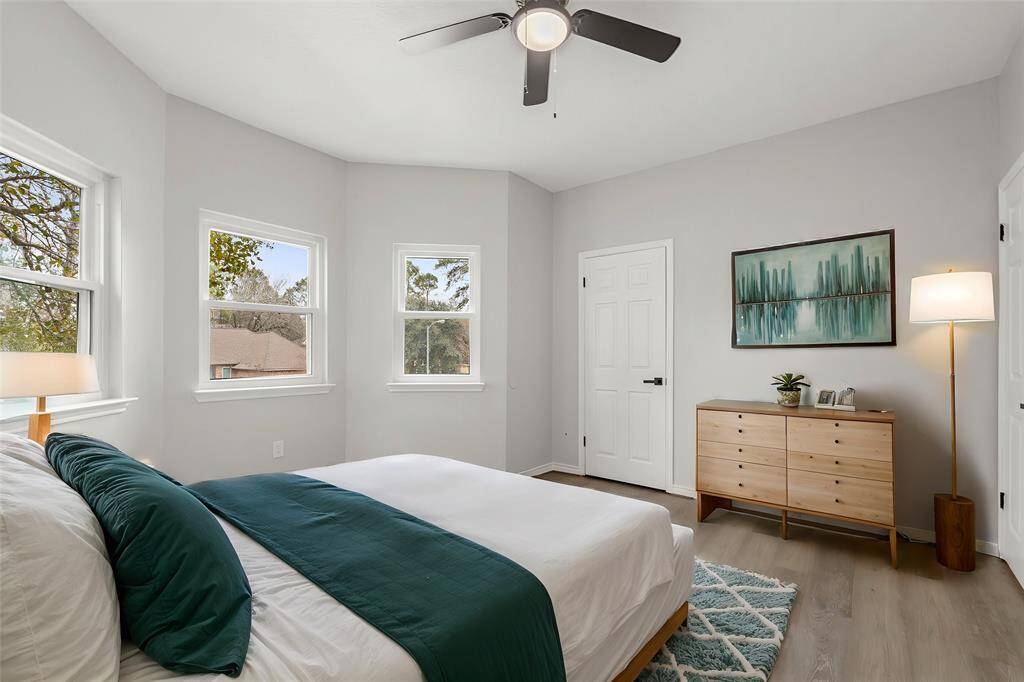 Virtually Staged: Beautiful secondary bedroom featuring neutral paint, vinyl plank floors, a dark wood stained ceiling fan, a built-in closet, and plenty of windows allowing tons of natural light.