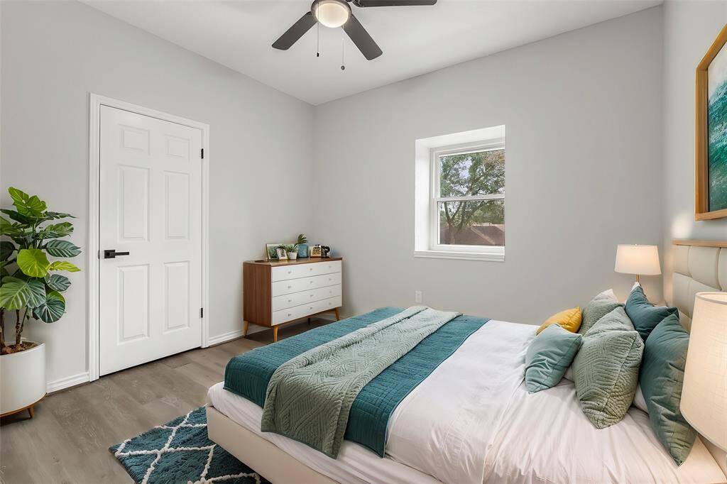 Virtually Staged: Beautiful secondary bedroom featuring neutral paint, vinyl plank floors, a dark wood stained ceiling fan, and a window.