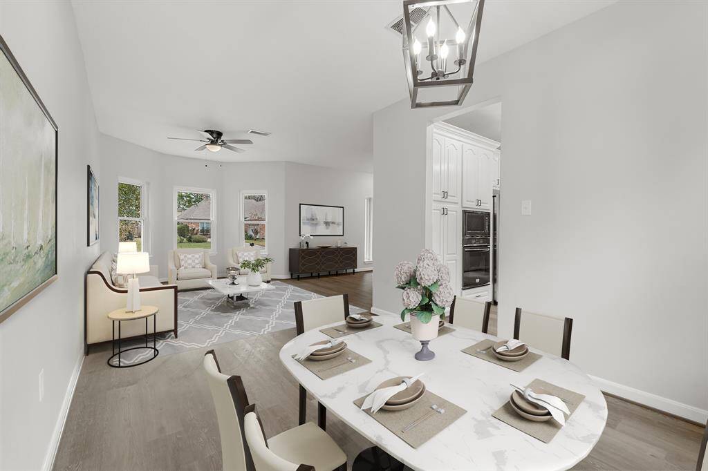 Virtually Staged: This beautiful dining area is ready for your next dinner party, featuring elegant lighting, vinyl plank floors, and easy access to the kitchen and living area!