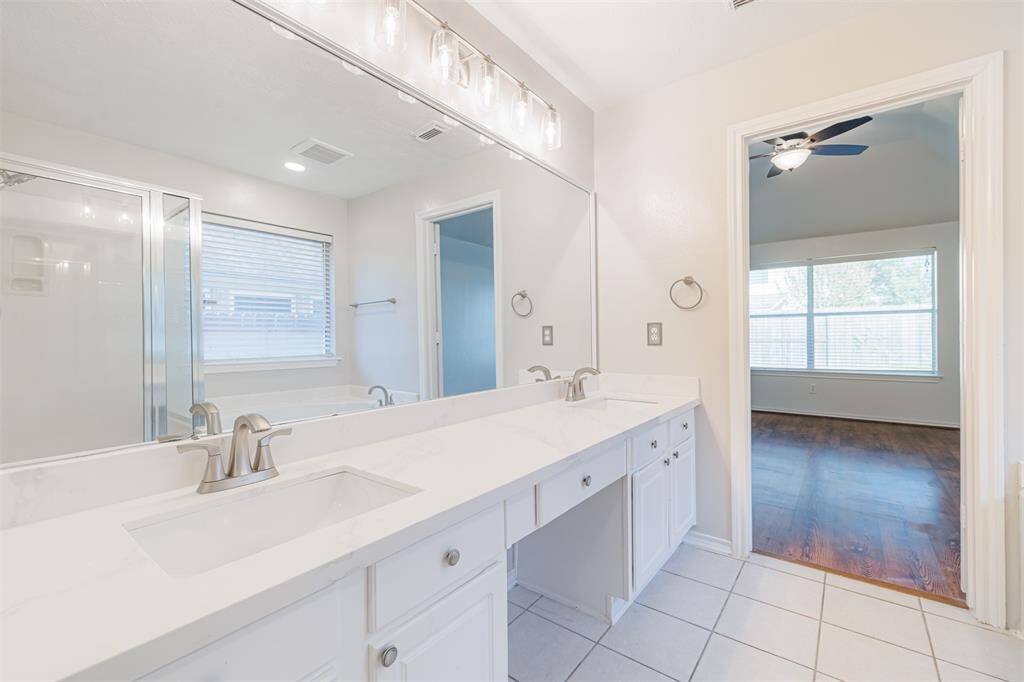 Primary bath with his and hers sink, plenty of light, and a vanity.