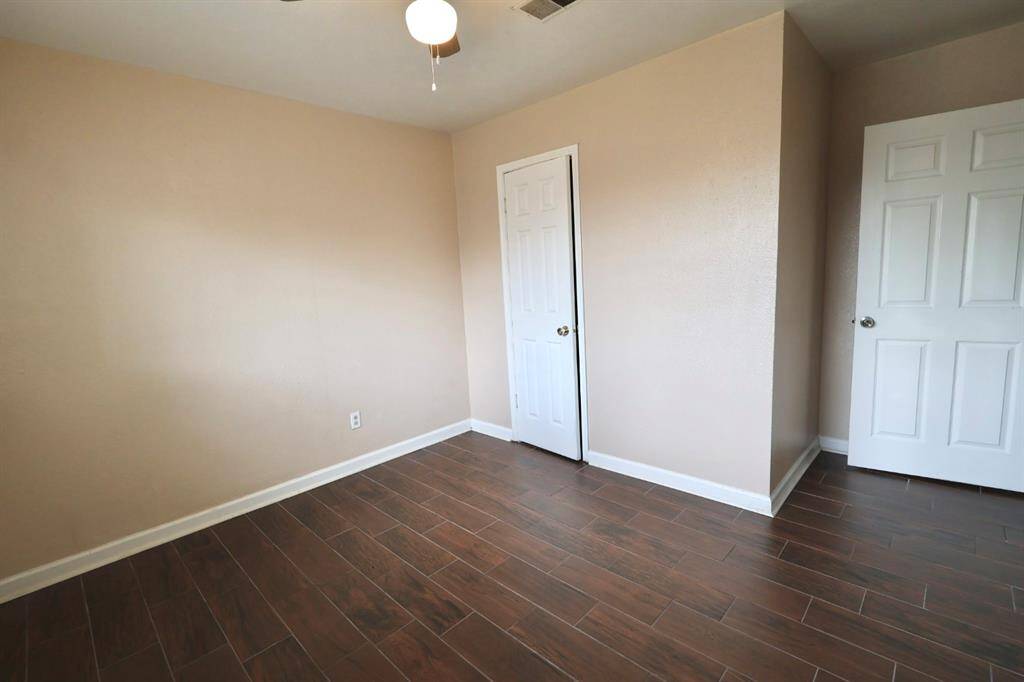 Deep-toned flooring and neutral walls, providing a perfect backdrop for any décor in the second bedroom