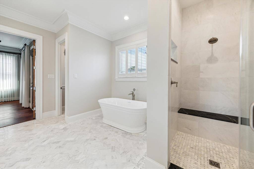 Spa-Inspired Retreat: Indulge in luxury with a serene freestanding soaking tub and an elegant walk-in shower featuring custom tile work. This tranquil space combines classic charm with modern comfort, perfect for unwinding after a long day.