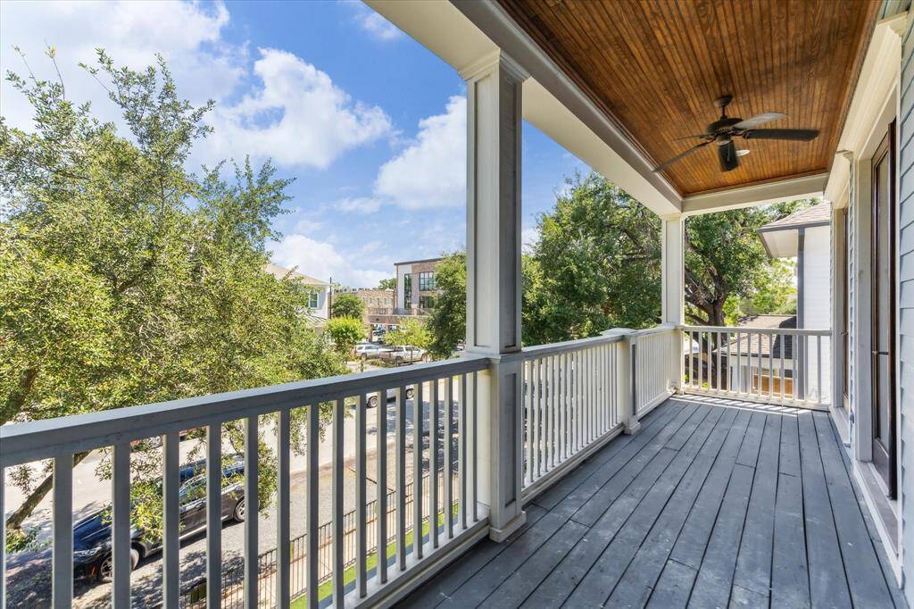 Charming Covered Balcony: Enjoy serene outdoor living on this expansive covered balcony, complete with a rich wood-paneled ceiling, ceiling fan, and classic white railing. A perfect spot for morning coffee or evening relaxation with sweeping neighborhood views.