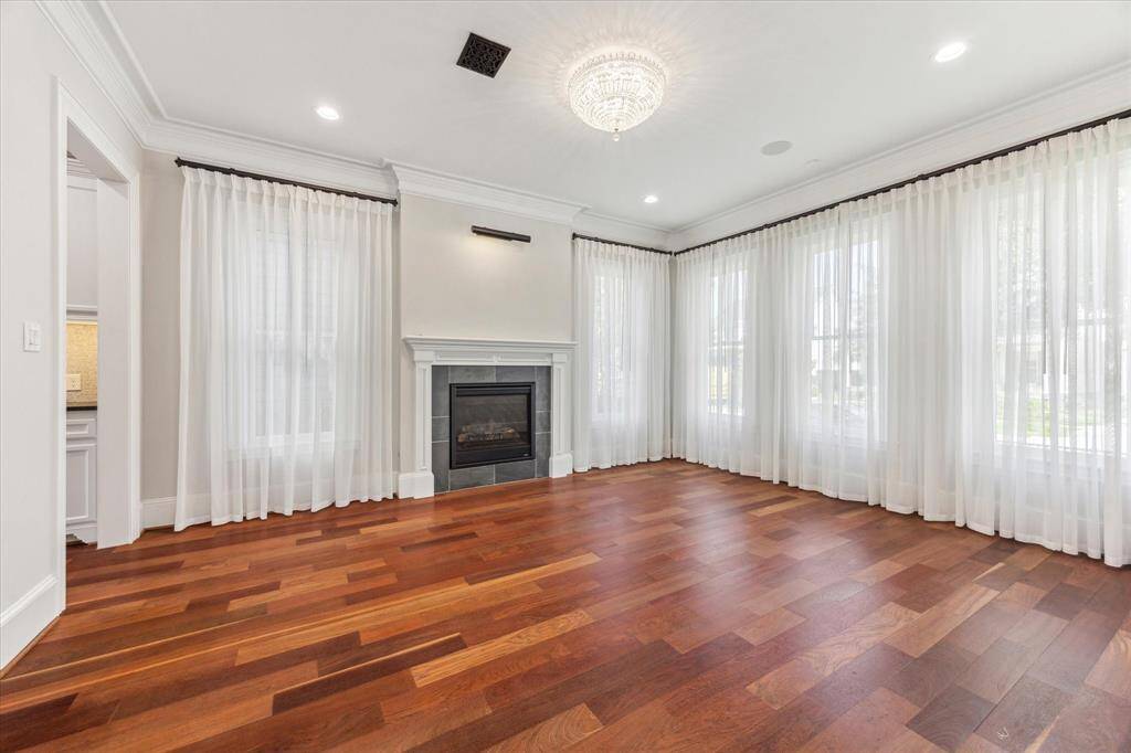 Elegant Retreat with Cozy Ambiance: This refined dining room/ living area boasts gleaming hardwood floors, a sleek fireplace, and soft, flowing drapes that bathe the space in natural light. A perfect setting for intimate gatherings or serene relaxation.