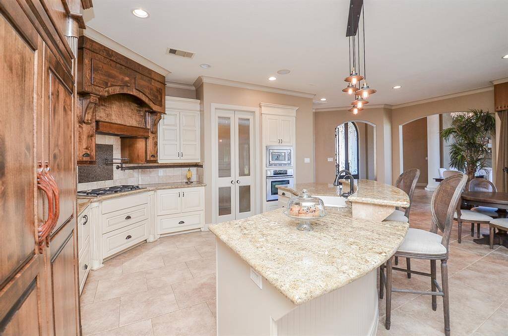 From another angle in the kitchen, you get a view of the curved counter that opens up to the living area, the front door, the breakfast and formal dining spaces. Behind the double see-through doors lies the butler's pantry, and within the butler's pantry, you'll find another set of doors leading to your pantry.