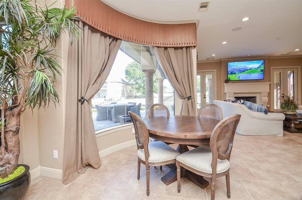 The breakfast area, situated to the left of the kitchen island, is also strategically positioned in front of a sizable curved window, maintaining a seamless connection with the captivating view.