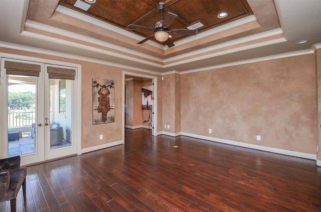 The upstairs family room is seamlessly integrated into the owner's suite, enhancing the sense of luxury and comfort. Take a moment to appreciate the doors leading to the upper balcony, where you can savor countless sunsets over the serene Lake Conroe.  The double doors in the back lead to the office.