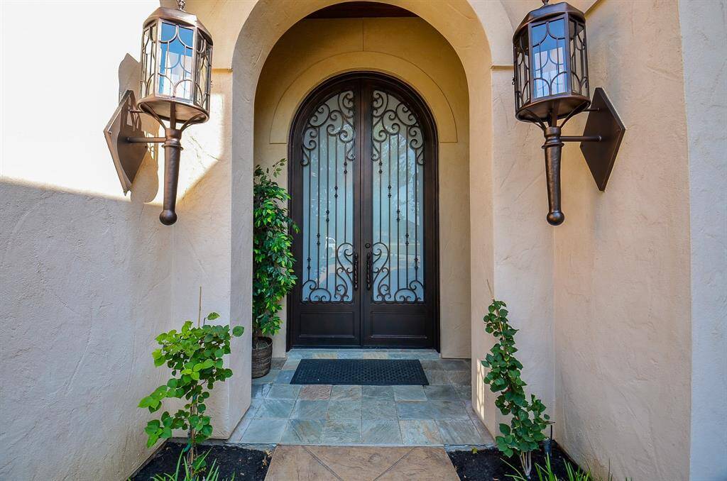 The front entry beautifully showcases oversized arched metal doors and elegant sconces.